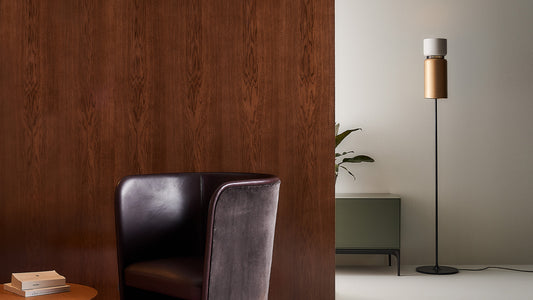 B.lux Aspen floor lamp with a brass shade beside a black leather armchair