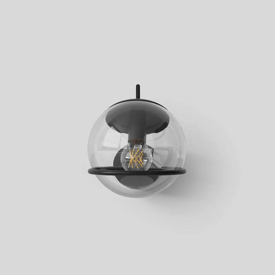 Astep 237/1 sconce installed as a bedside reading light with upward-facing clear glass sphere in black frame.