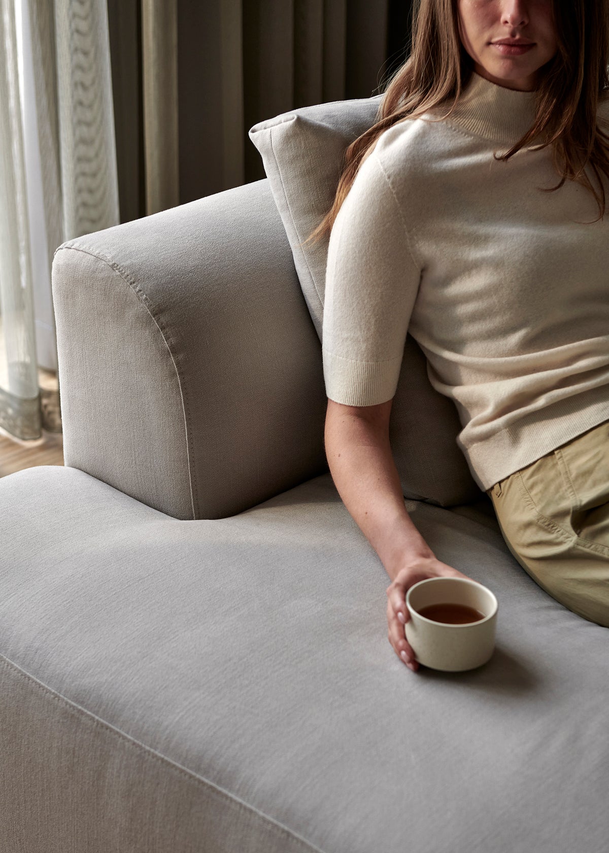 blomus MAKOTO Handleless Stoneware Cups – Moonbeam tea cup in hand on a sofa