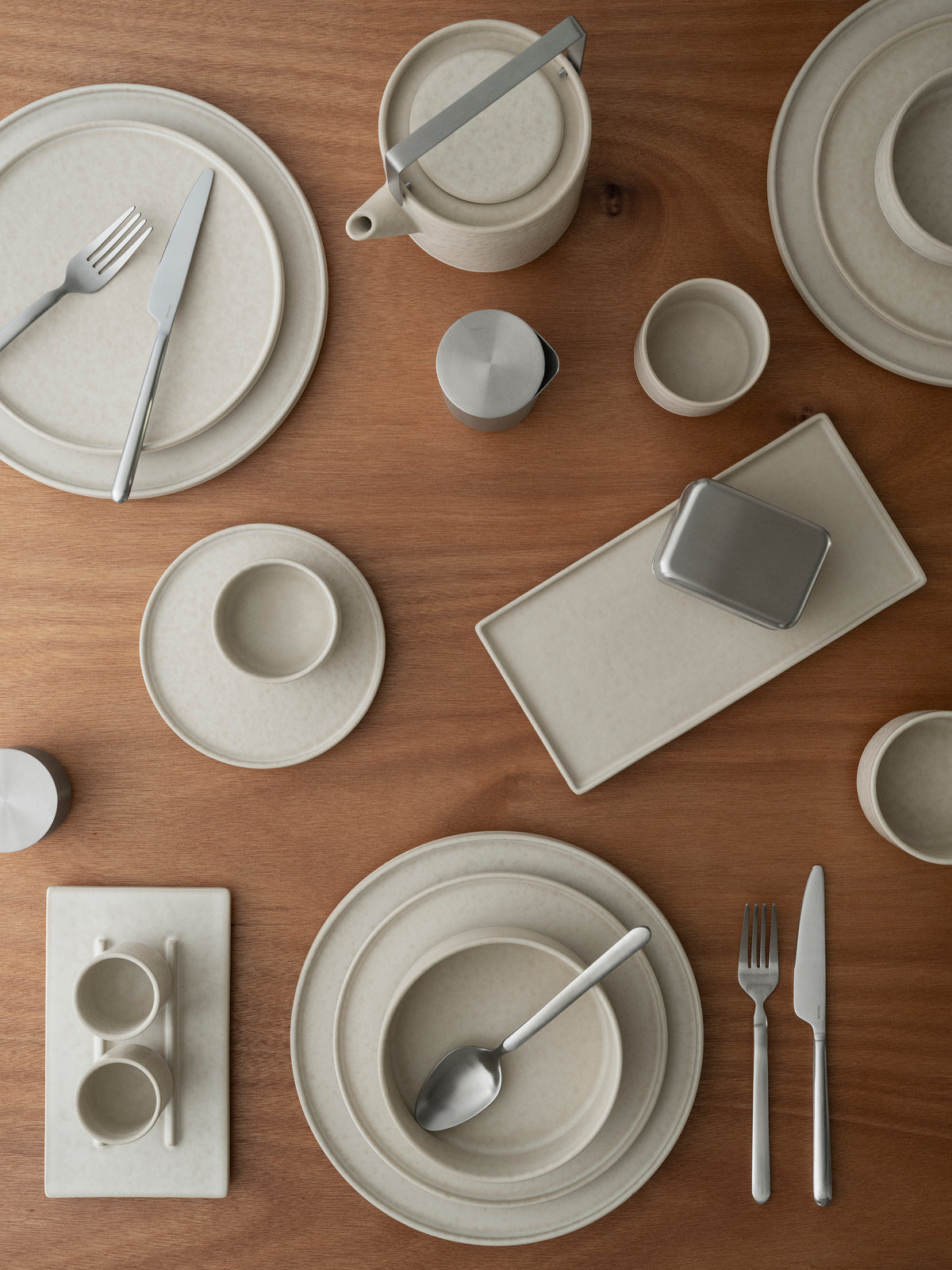 blomus MAKOTO Stoneware Plates: Dinner, Dessert & Side – Moonbeam plates, bowls and cups set on an oak table