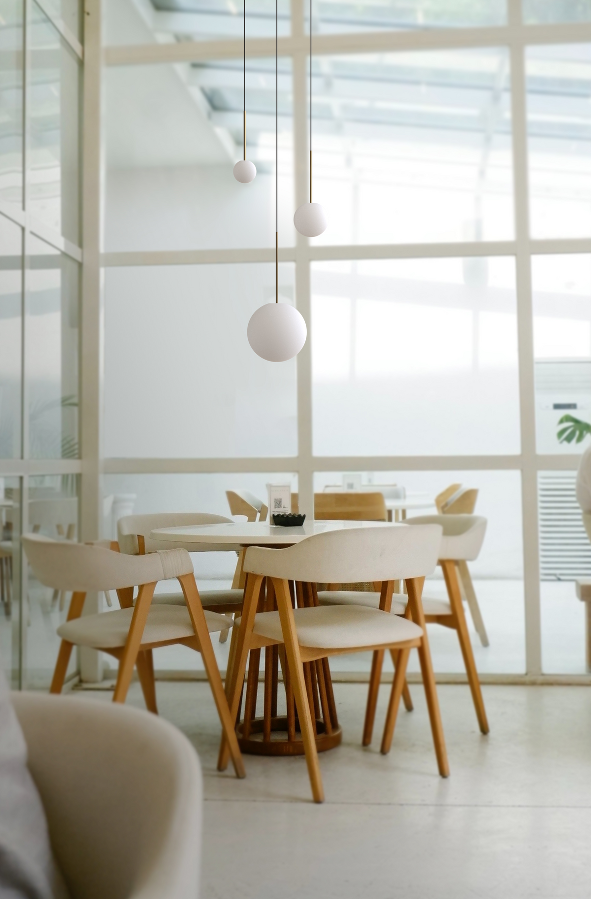 Bola opal globes hanging over a dining table in a bright room