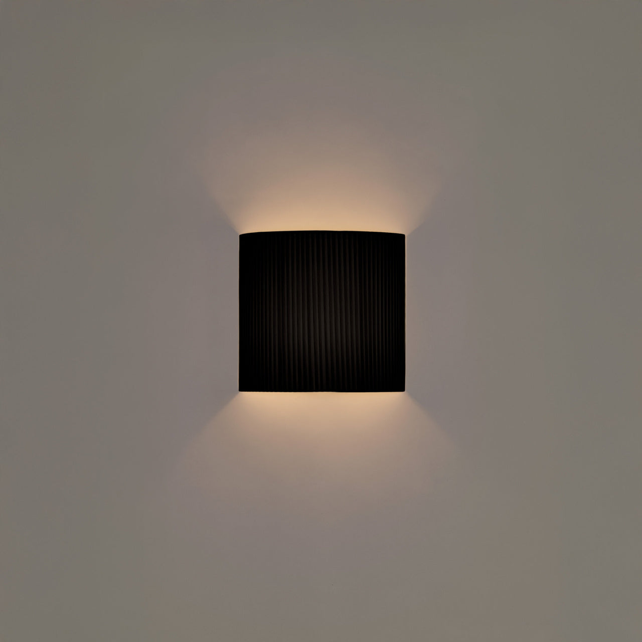 Minimalist black ribbon wall lamp by Santa and Cole with warm ambient lighting