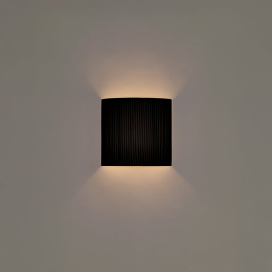 Minimalist black ribbon wall lamp by Santa and Cole with warm ambient lighting