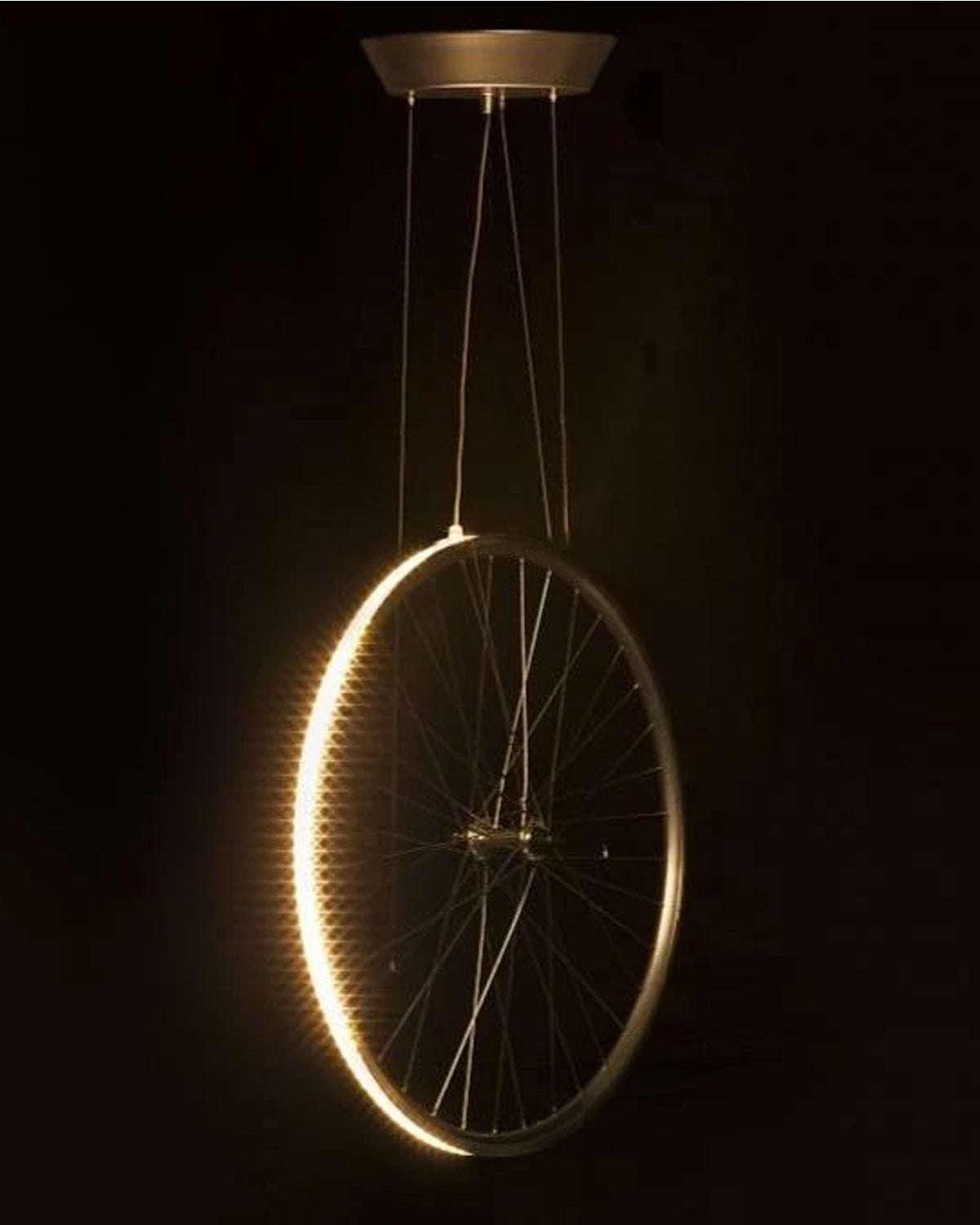 Cyclampa Eddy LED pendant lit at night, glowing aluminum wheel rim