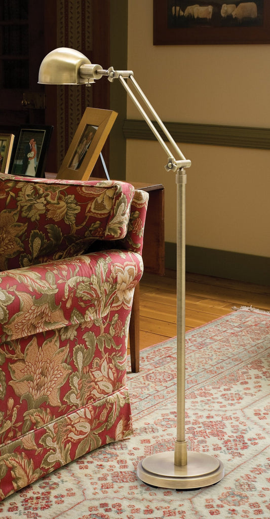 House of Troy Addison Adjustable Pharmacy Floor Lamp in Antique Brass in a room setting