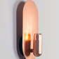 Luxurious copper Innermost Brixton wall fixture, casting indirect light in a contemporary living room space.