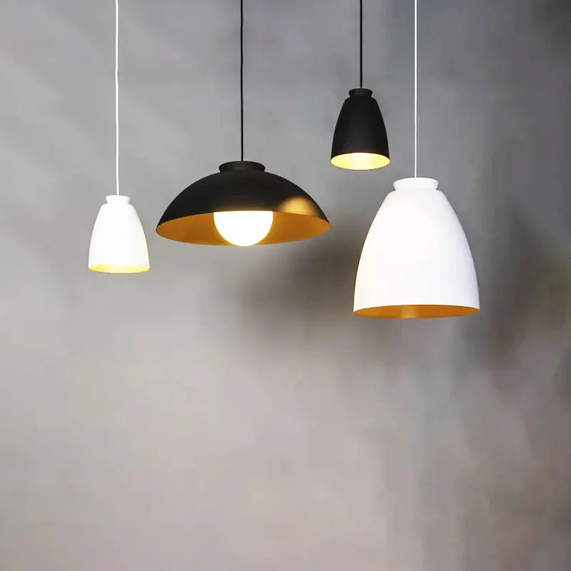 Four pendant lights with different colored shades hanging against a gray background