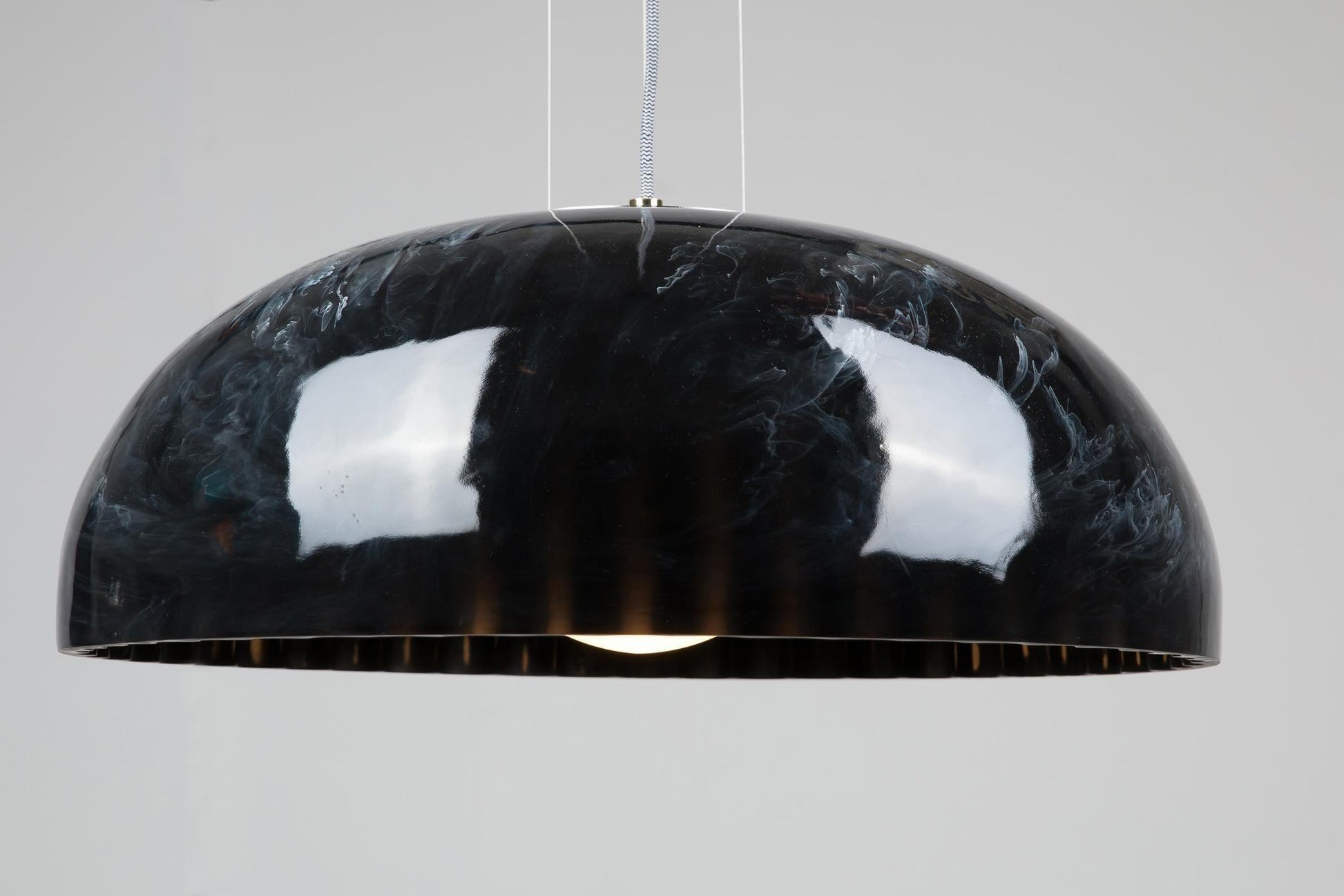 Innermost Doric 60 LED pendant light in polished black marble finish, hanging over a modern dining table.