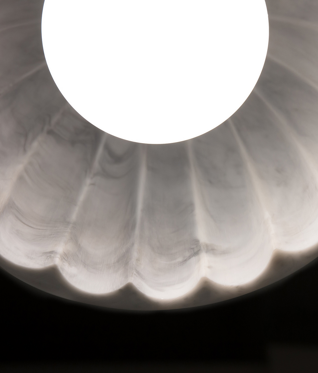 Close-up of Doric 28 LED pendant's unique scalloped interior detail on a rose marble resin shade.