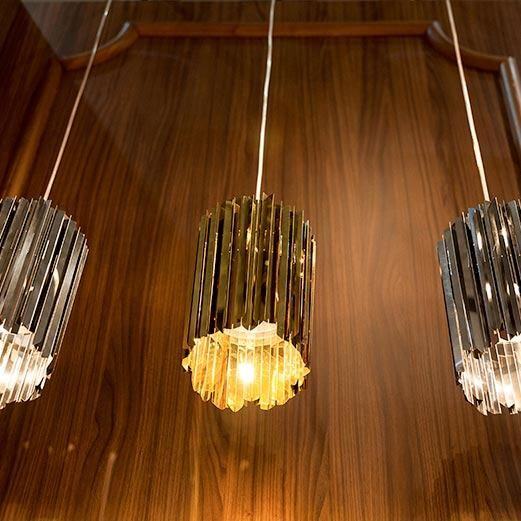 Innermost Facet 18 mini pendant light by Tom Kirk – Polished Brass against a wood wall