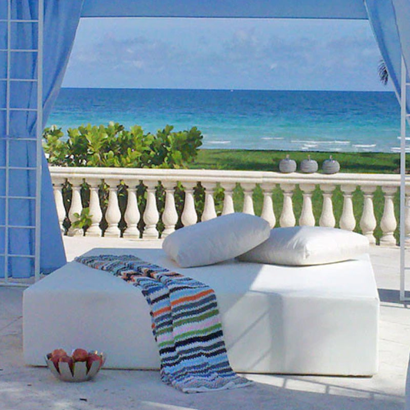 White Play Pad resort bed beside a striped blanket under a seaside cabana