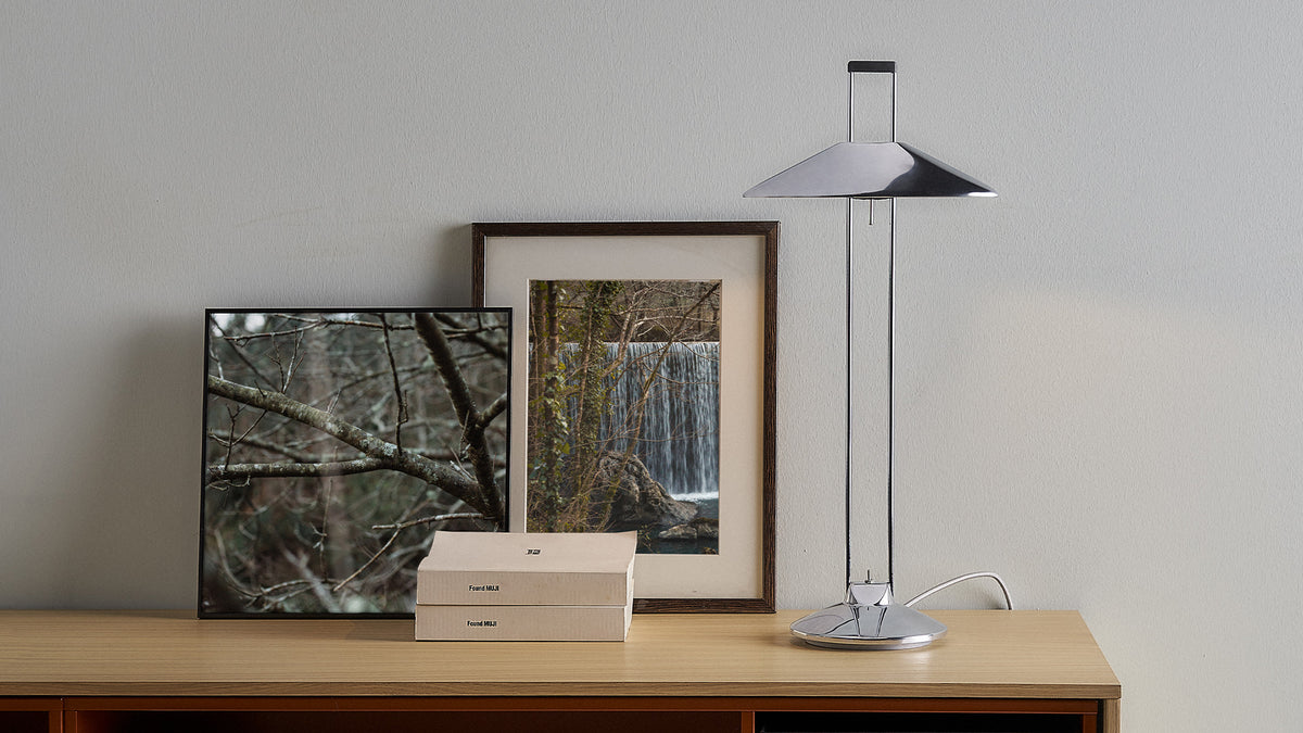 Regina T table lamp by Jorge Pensi in aluminium beside framed art on a wooden console