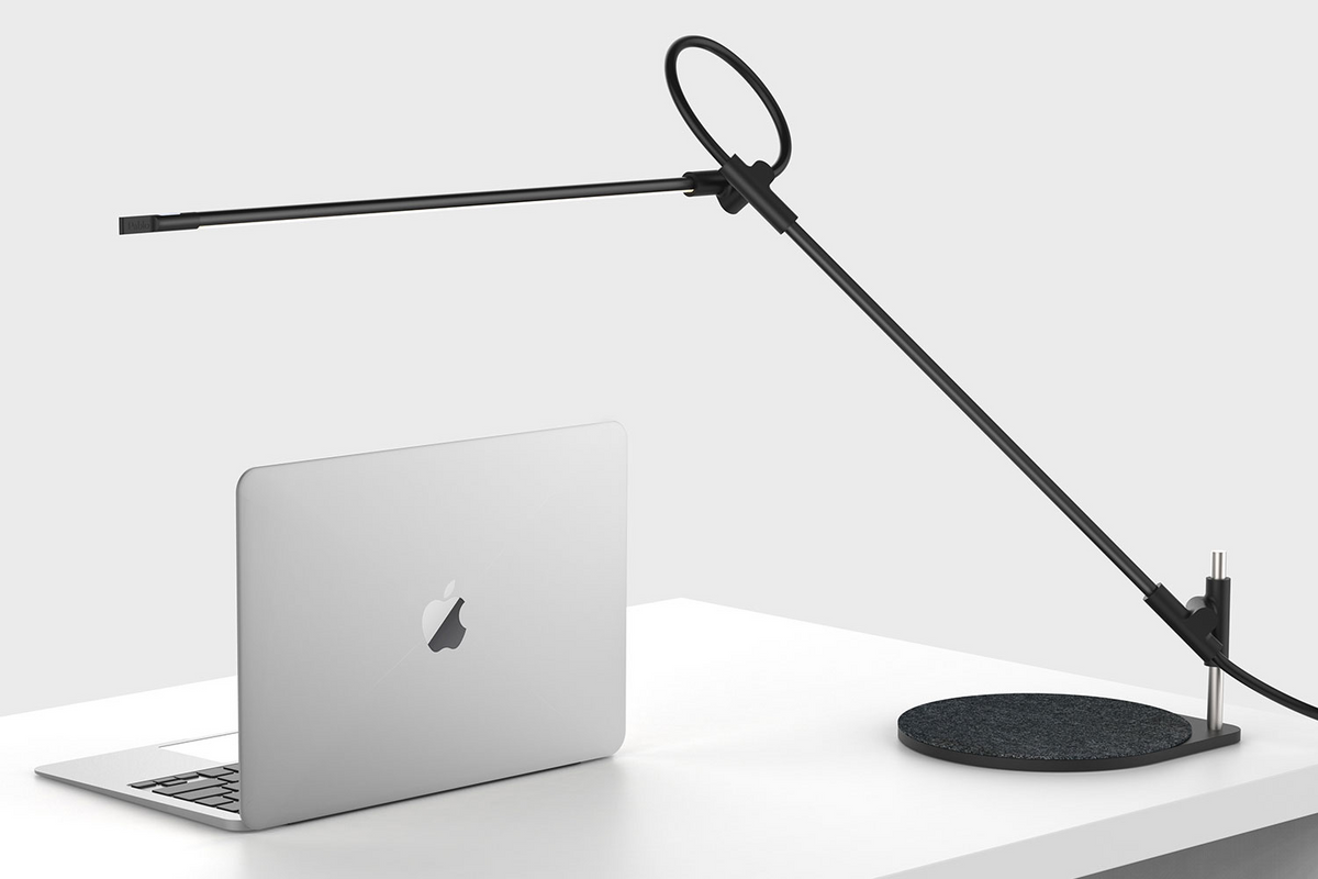 Superlight table lamp with its arm raised over a desktop
