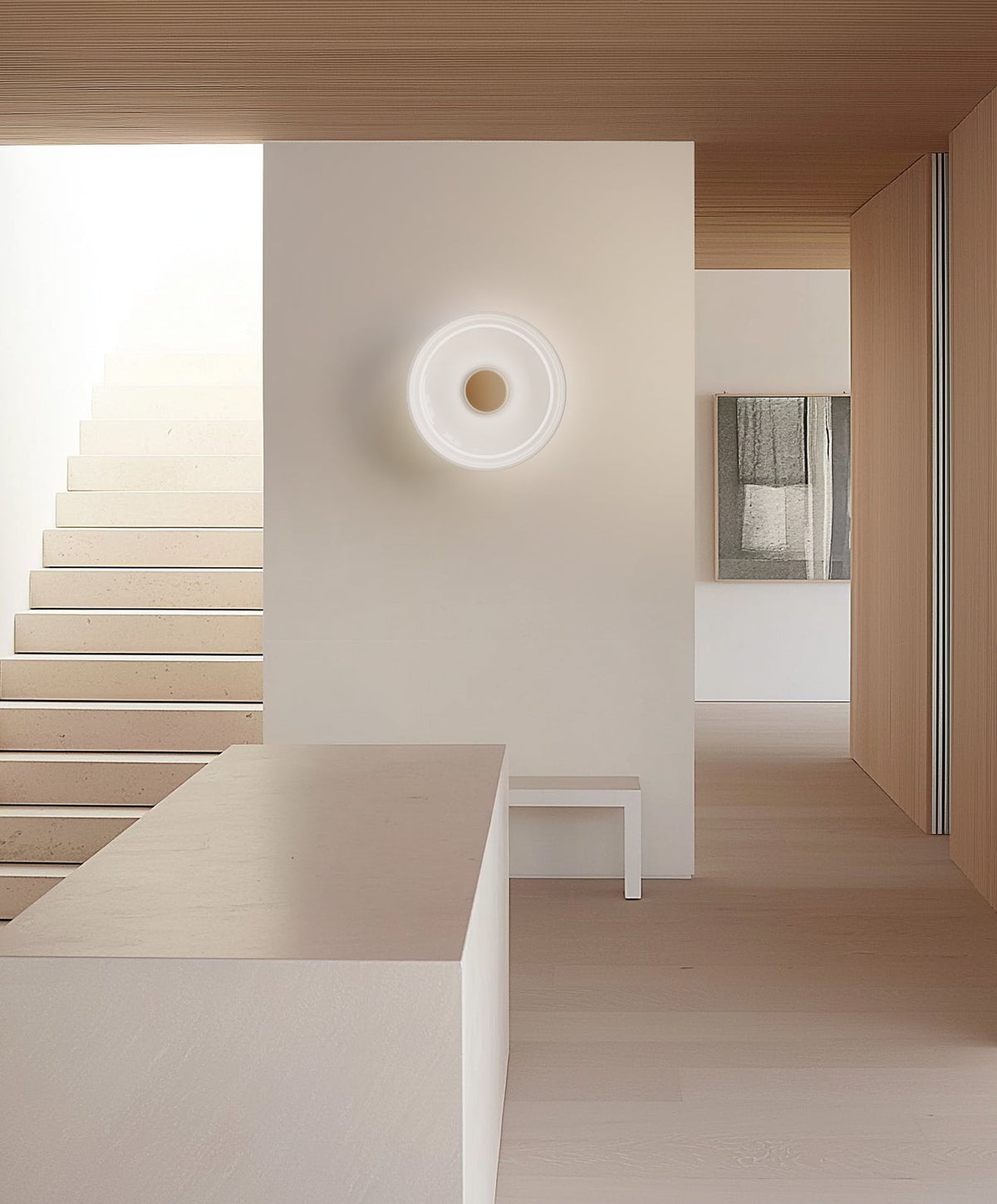 Opal glass sconce on a wall at the top of a pale staircase hallway