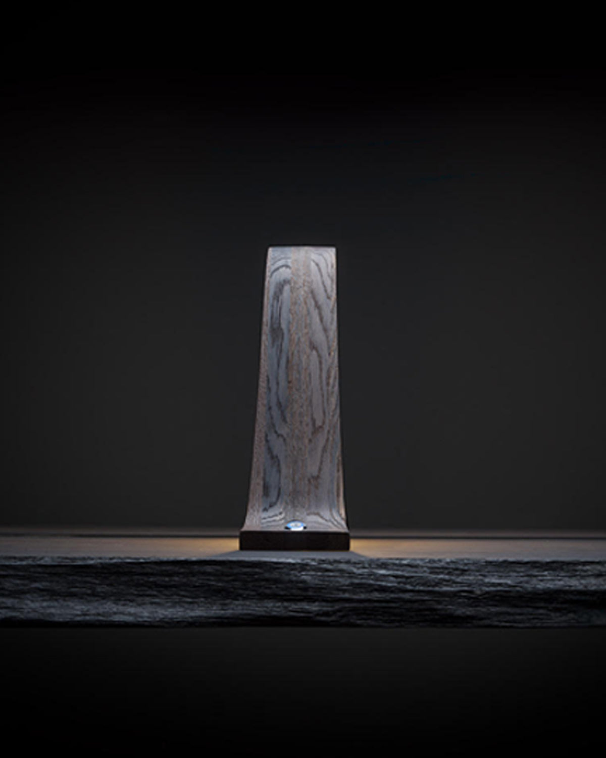 Teukho Lambda fossil oak LED table lamp in Black, end-on profile on a dark surface