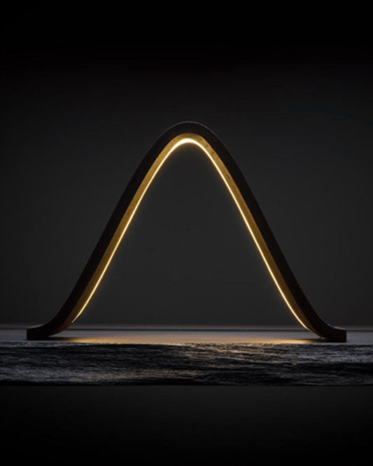 Teukho Lambda fossil oak LED table lamp in Black glowing on a dark stone surface