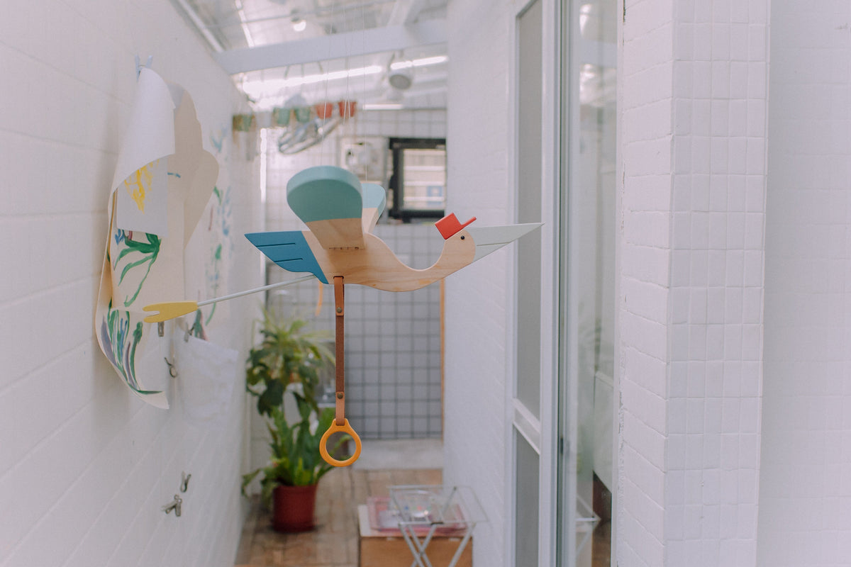 Eguchi Toys Bird Mobile Medium, Blue – hanging in a bright hallway