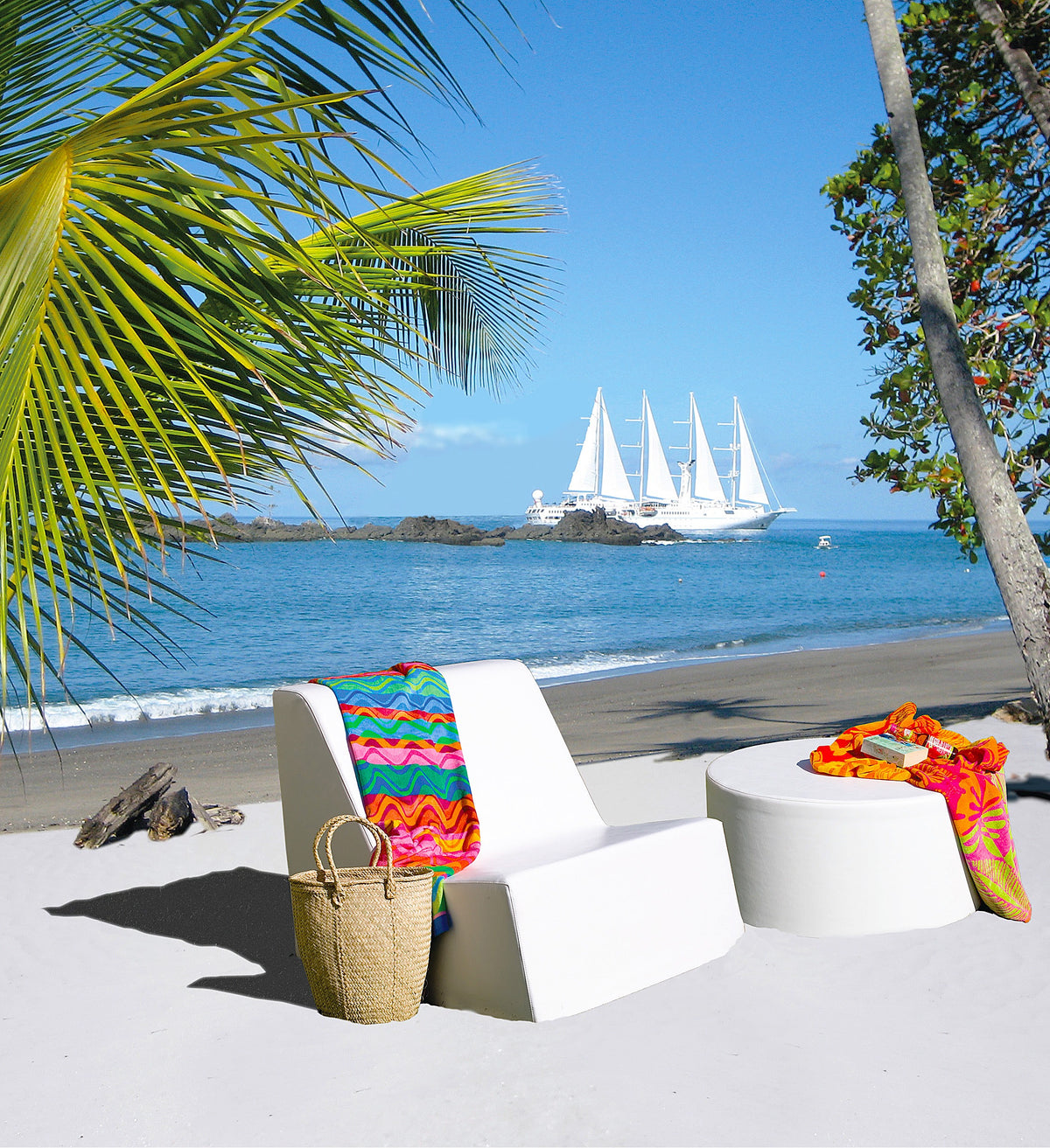 White Puck round ottoman beside a Check chair with a colorful throw on a beach with sailboats