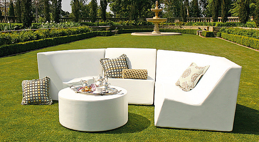 White Puck ottoman as a coffee table with a tea tray in front of a curved sectional on a lawn