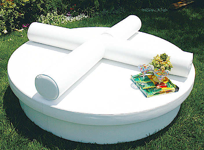 Two white Roll bolsters crossed on a round Sun Pad on a lawn with a tray and flowers