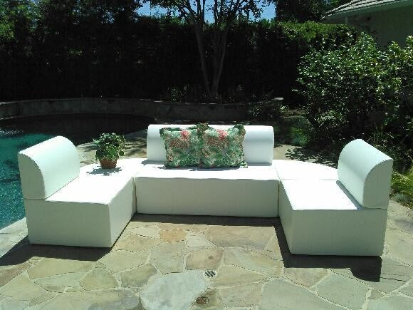 Two Zig armless outdoor chairs in white marine vinyl flanking a Zig Duo bench on a stone patio beside a pool