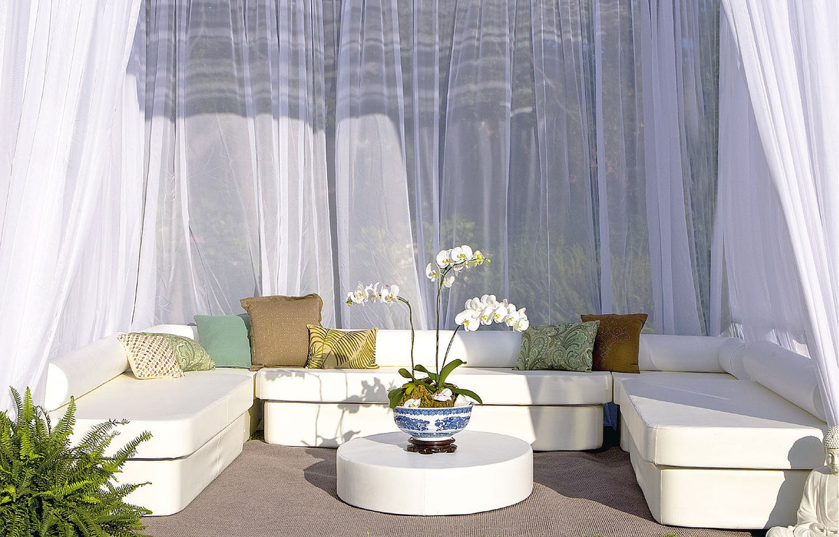 Modular Cot and Stand seating with sheer curtains and an orchid centerpiece forming a U-shaped cabana