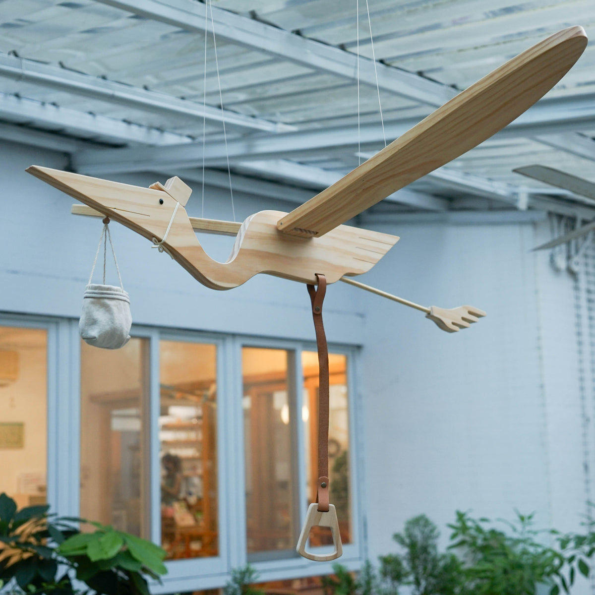 Eguchi Toys Stork Mobile Large, Wood – hanging in a garden courtyard