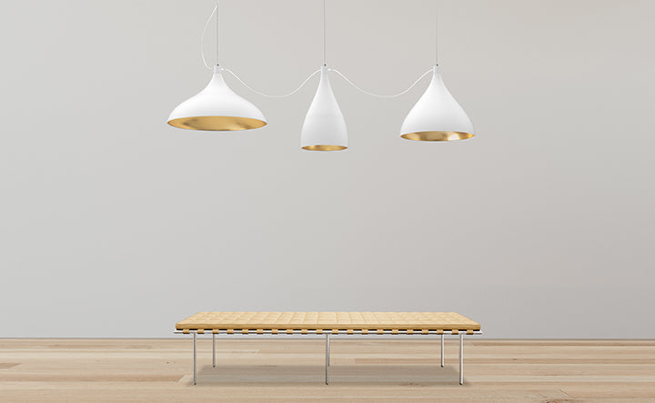 Pablo Designs Swell XL pendants in white and brass above a wooden bench