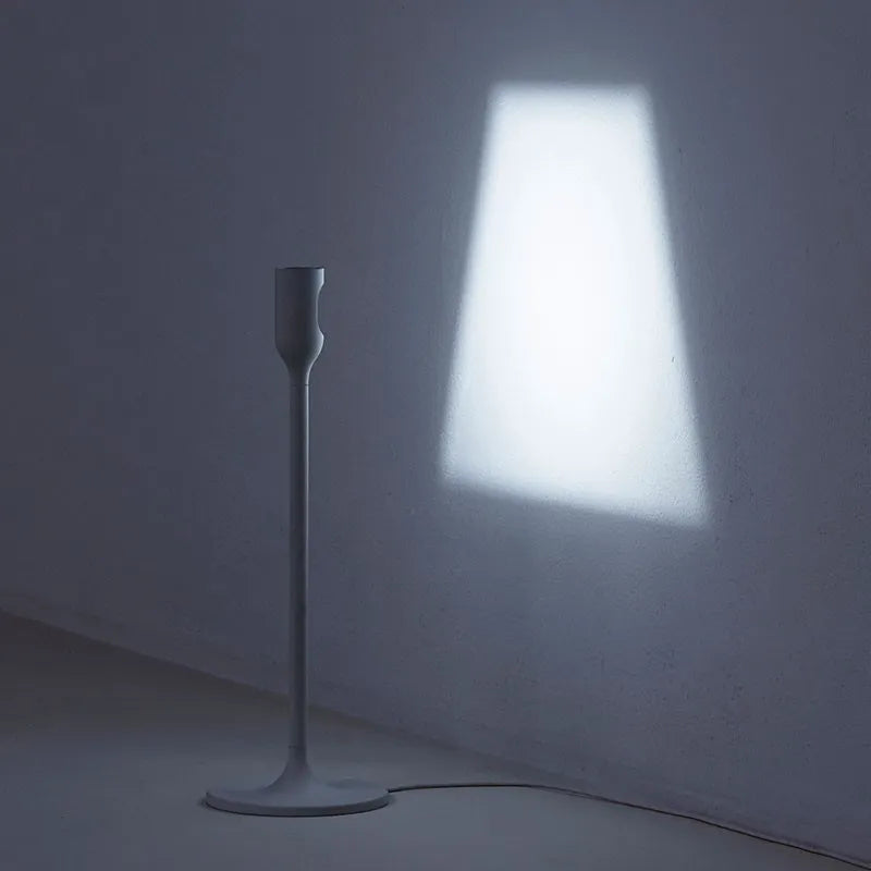 Sleek aluminum and steel Yoy table light from Innermost, casting a distinct lampshade outline on a textured office wall.