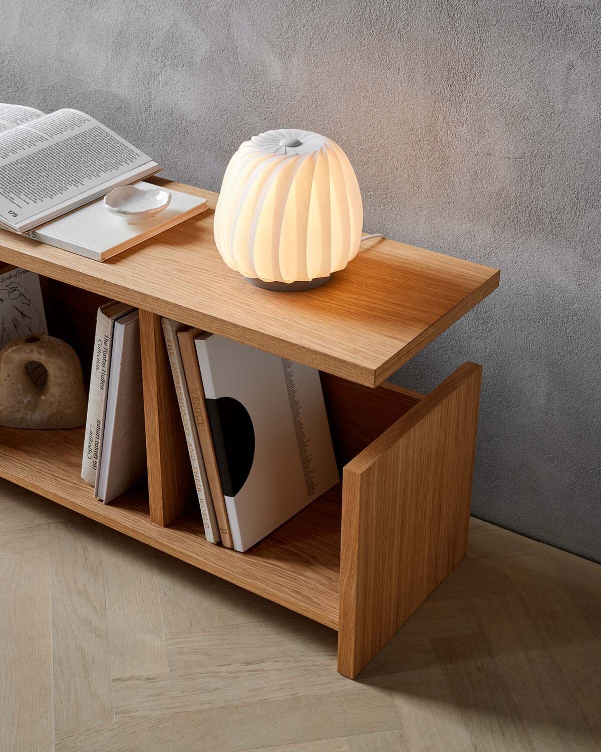 Tom Rossau ST906 Mini table lamp – White Coated Paper, lit on a bookshelf