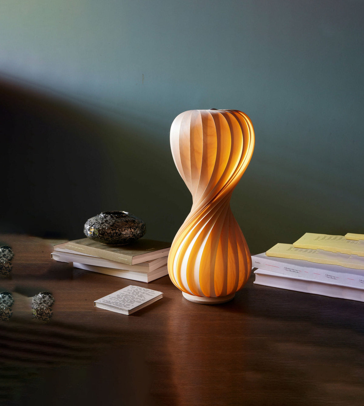 Tom Rossau TR7 table lamp – lit on a desk with books